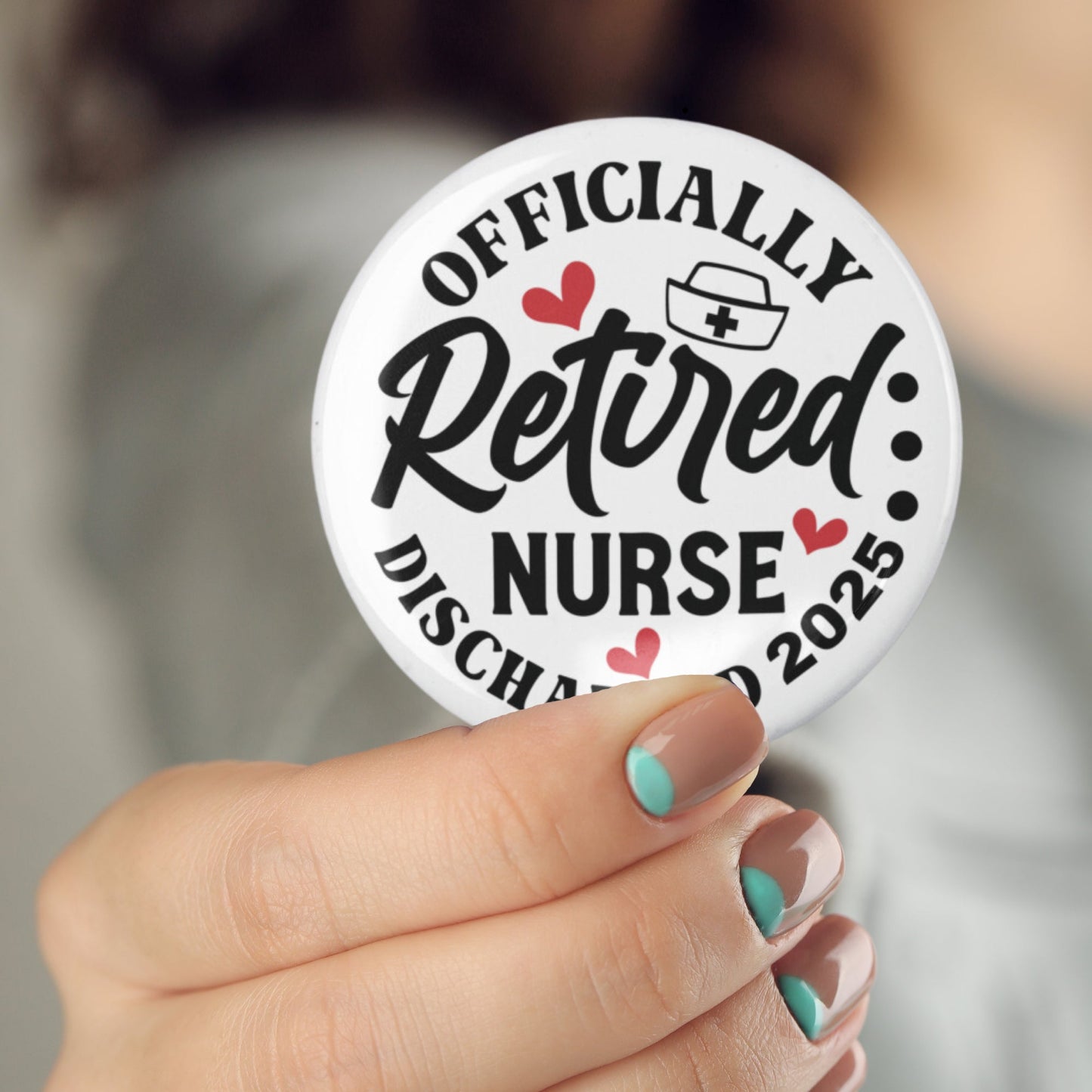 A person showcasing a Retirement Nurse Gift Badge on their shirt, displaying 'Officially Retired Nurse Discharged 2025', a charming accessory for celebrating a retired nurse. A lovely option among goodbye gifts for nurses.