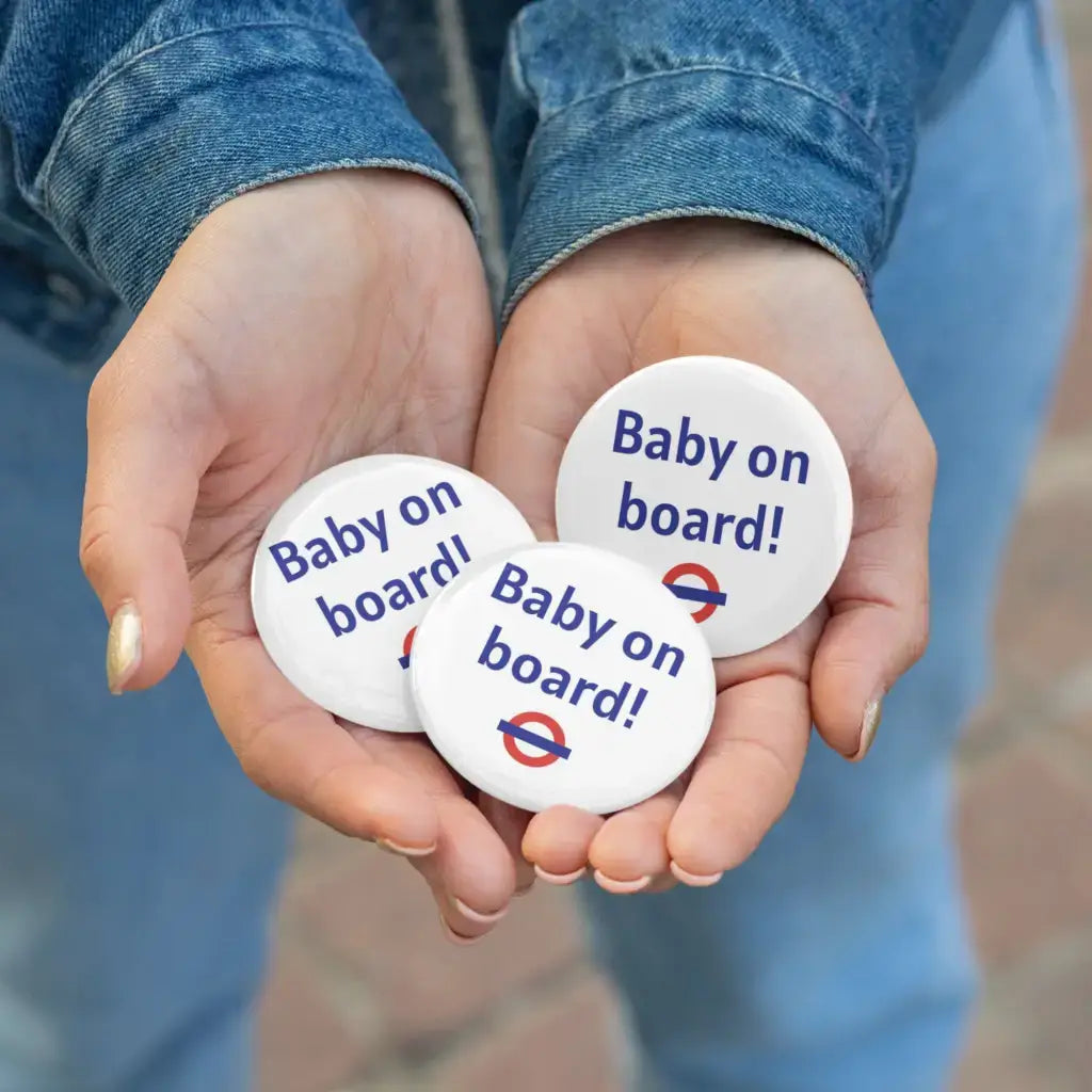 Three EMU Works Baby On Board Pins being held in hands, showcasing the trendy design perfect for announcing a pregnancy.