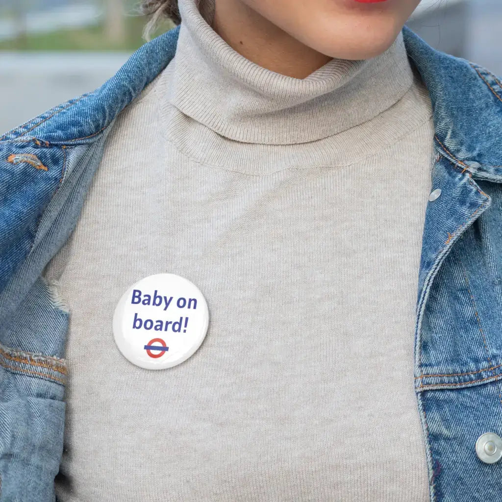 A close-up of a person wearing the EMU Works Baby On Board Pin on a sweater, highlighting its stylish addition to any outfit.