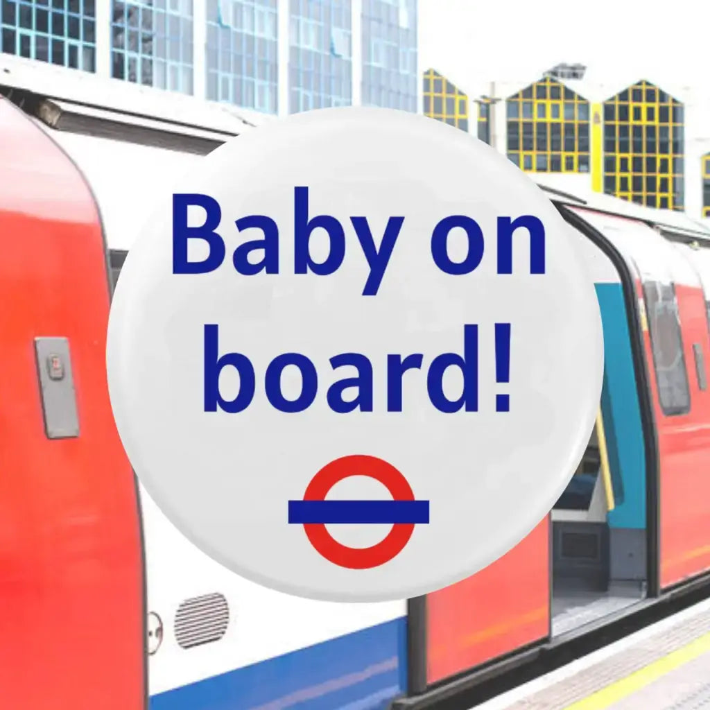 The EMU Works Baby On Board Pin prominently displayed in front of a London Underground train, merging style with location for pregnancy announcement.
