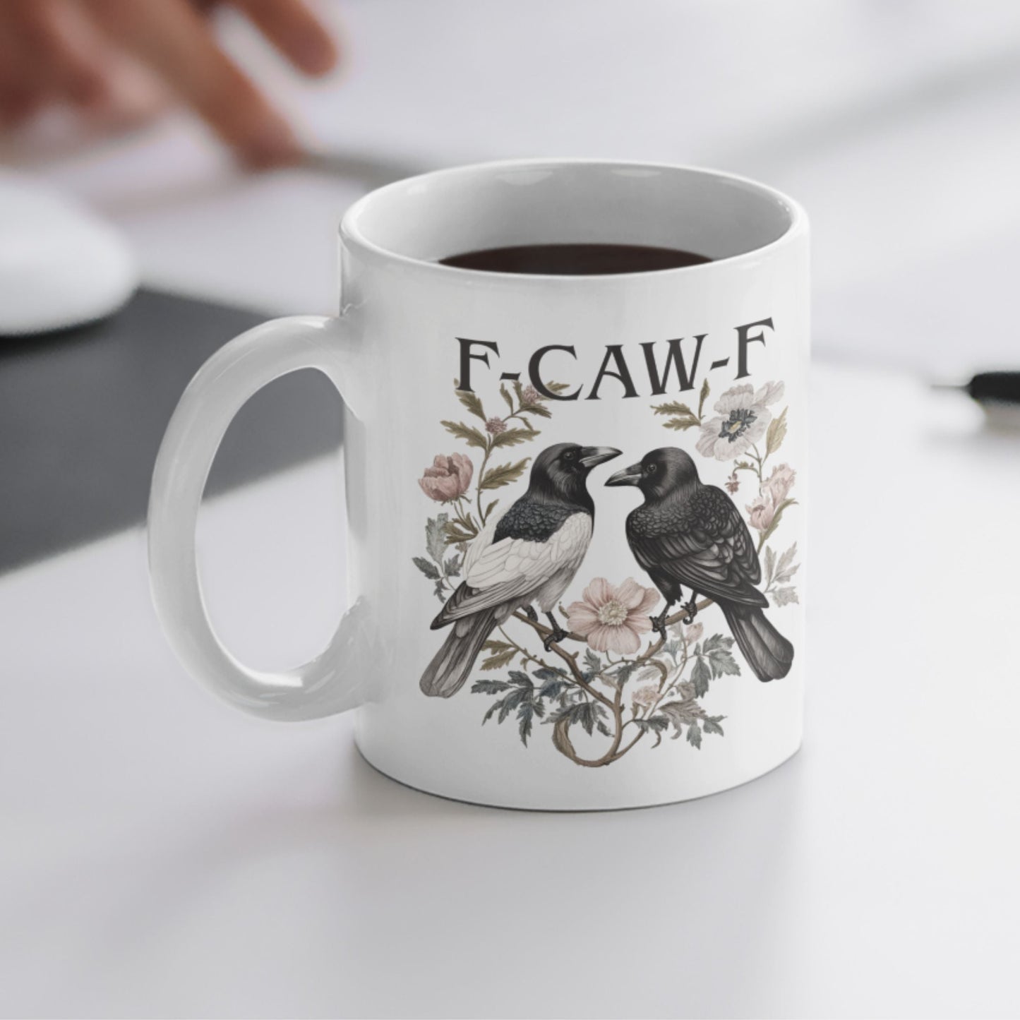Funny Swear Words F Caw Halloween Mug with a crow design in a cosy setting, perfect for sipping coffee. This gothic coffee cup is a charming addition to your Halloween collection.