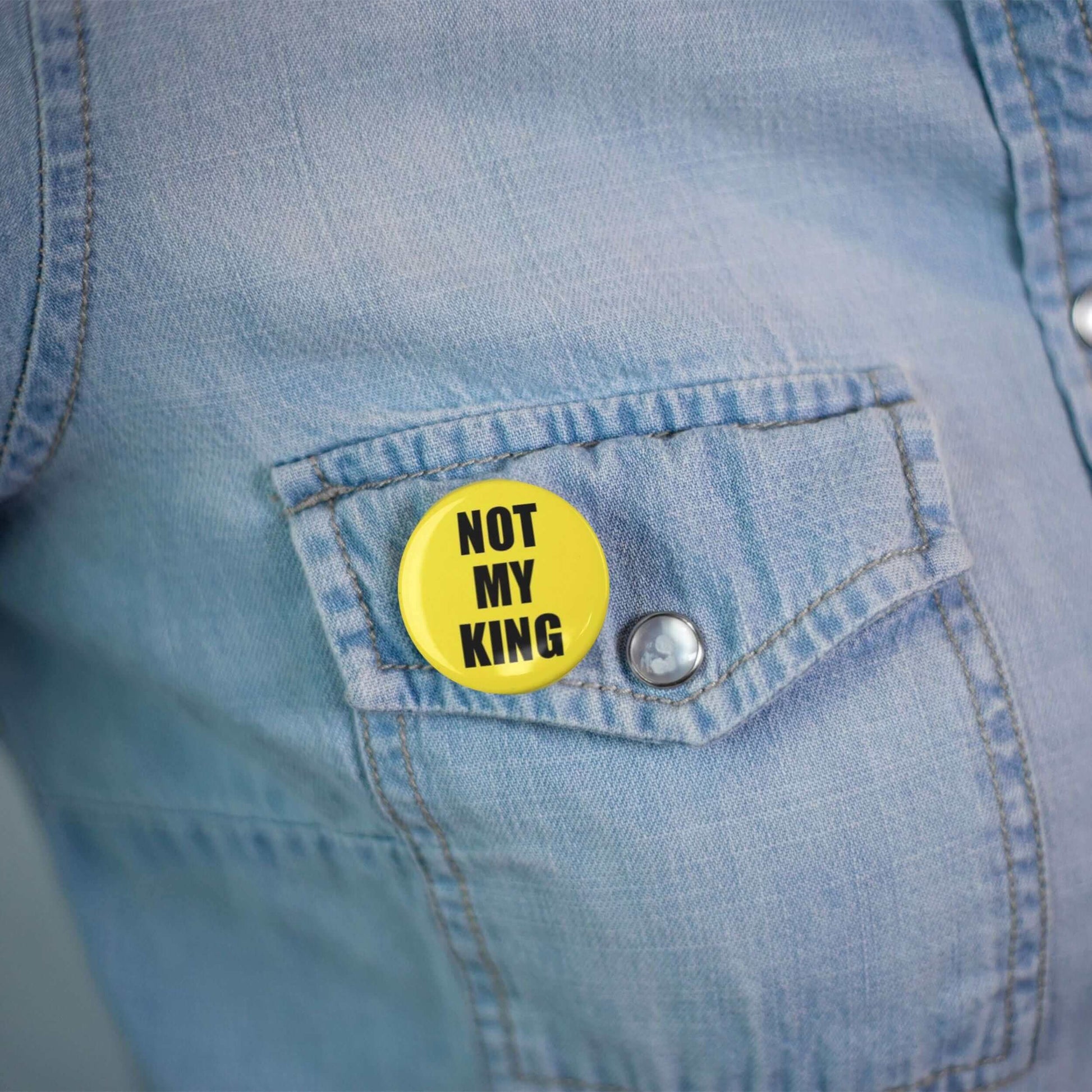 Yellow 'Not My King' pin badge on denim jacket pocket, anti-monarchy, political statement accessory, 25mm size.