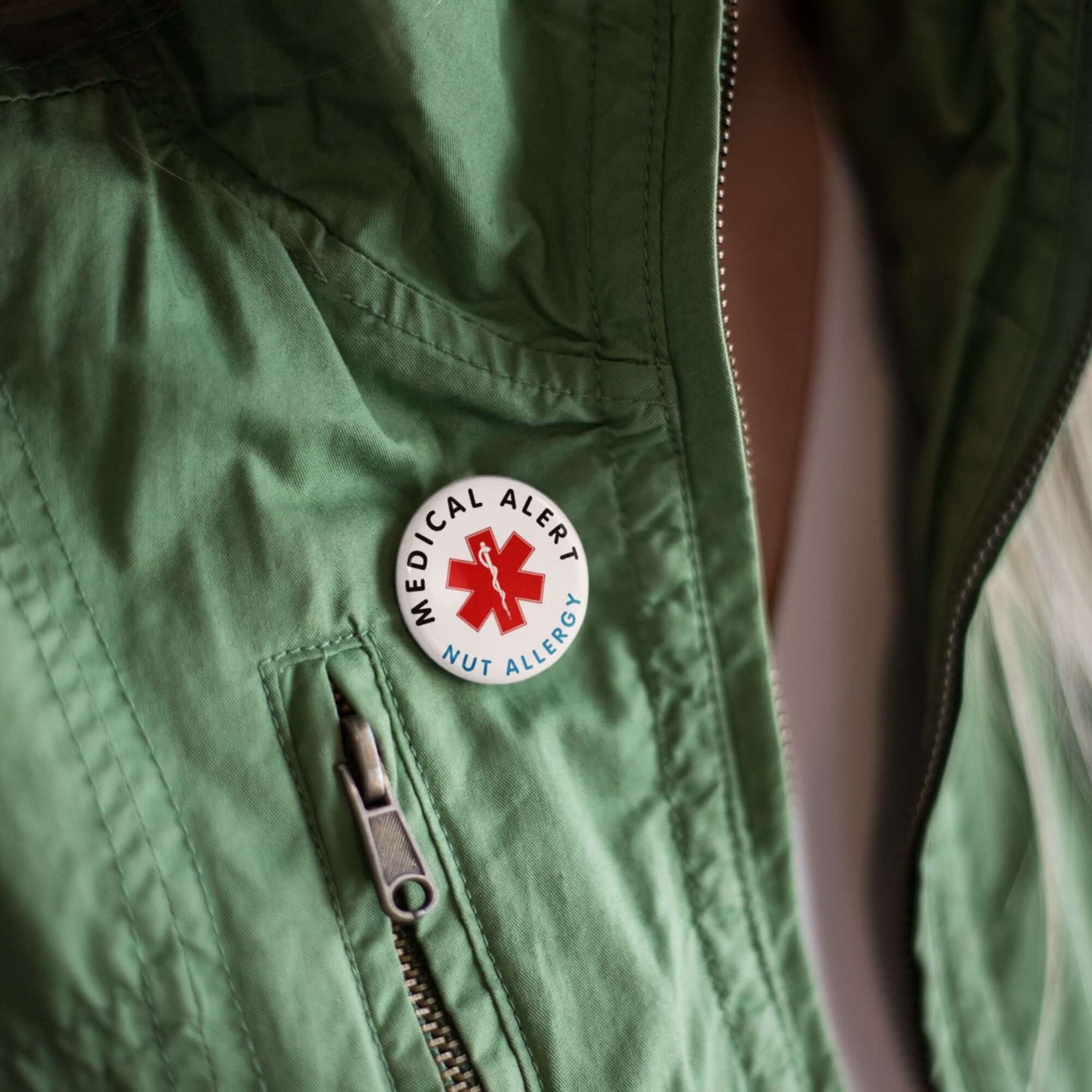 Nut Allergy Awareness Badge - 1 Inch Medical Alert Logo Pin displayed on a green jacket to promote nut allergy awareness.