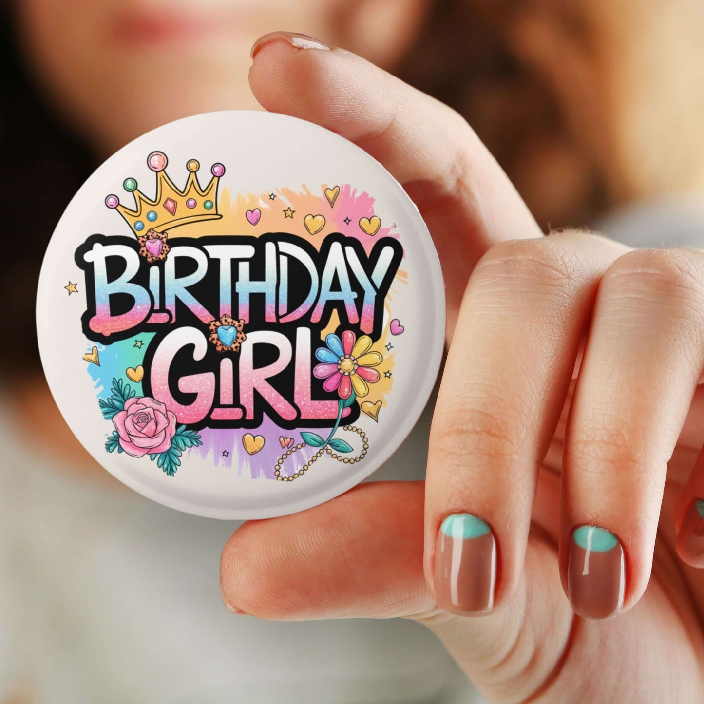 Colorful Birthday Girl badge held in hand, featuring a crown and floral designs for festive birthday celebrations.