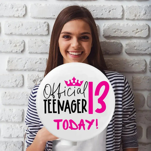 Teenage girl holding an official 13th birthday badge, showcasing her excitement for her special day.