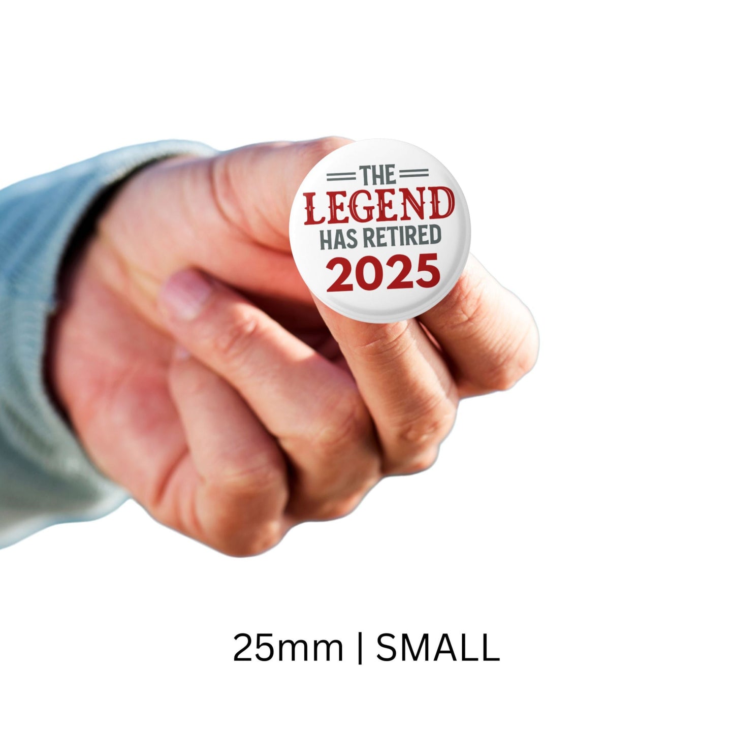 A hand holding the small 25mm Retirement Badges 2025 pin, featuring the phrase 'The Legend Has Retired 2025'.