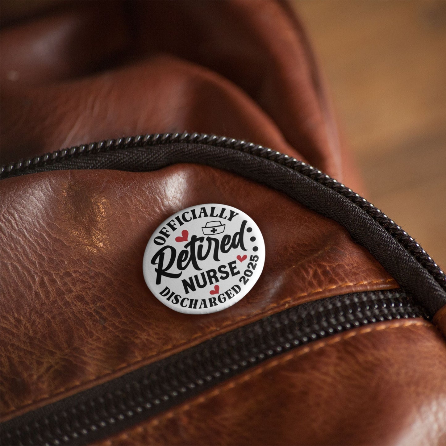 The Retired Nurse Badge - Officially Retired 1 Inch Health Awareness Pin Button Badge placed on a stylish bag, highlighting its portable design.