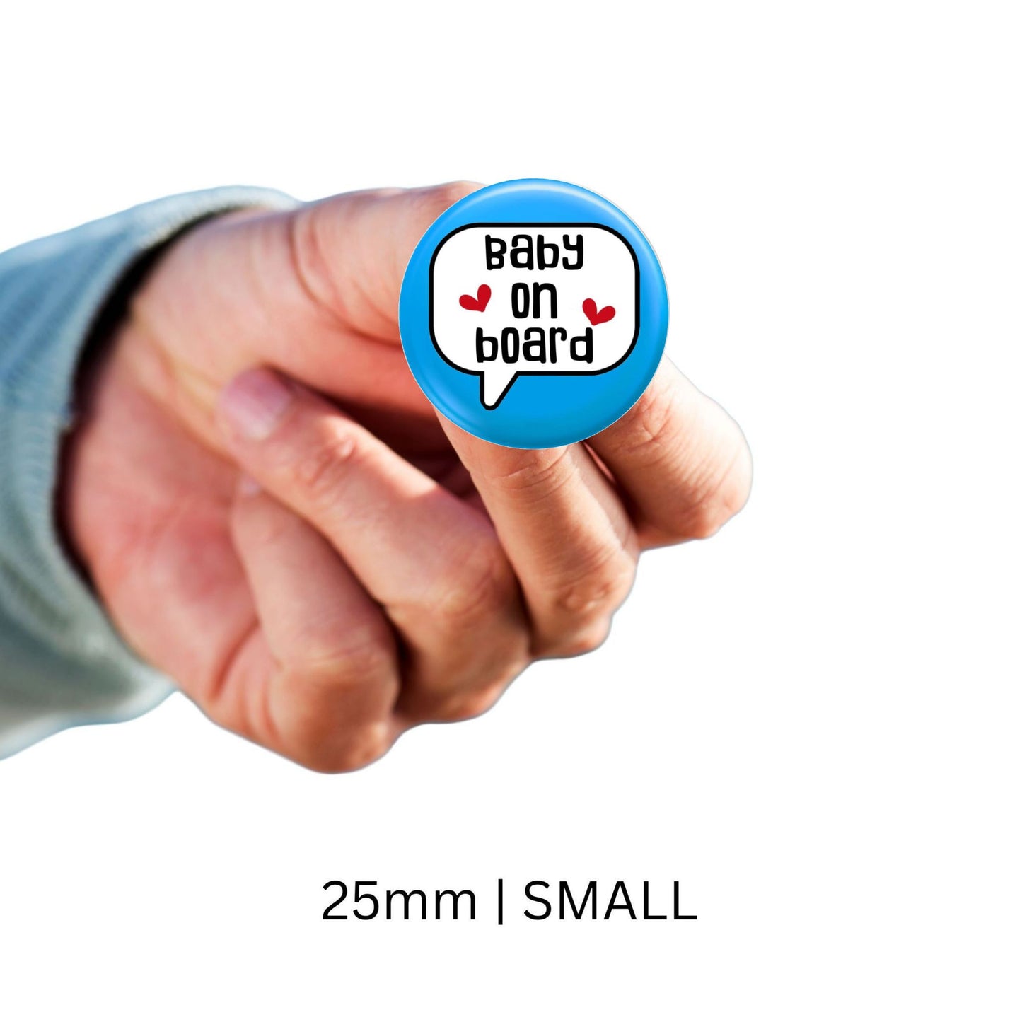 Individual holding a small blue baby on board badge, size 25mm, promoting pregnancy awareness in a casual setting.
