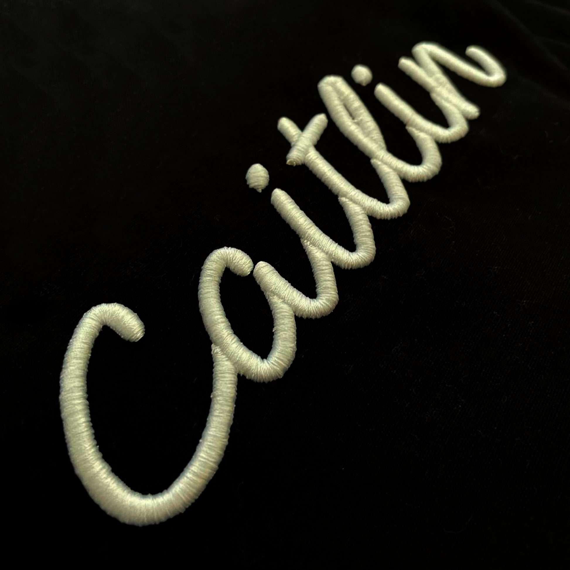 Embroidered name 'Caitlin' on a black background