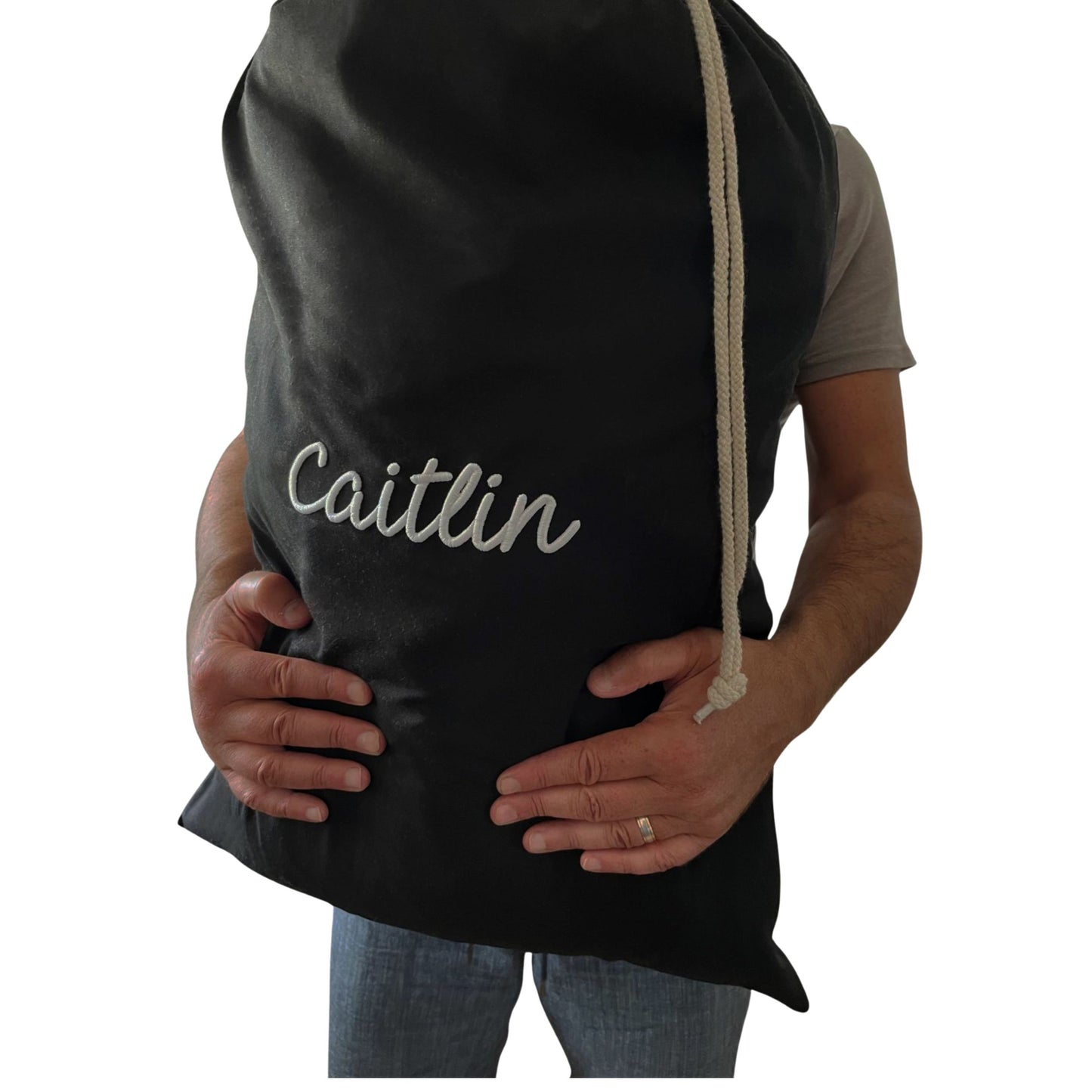 Person wearing a black apron with 'Caitlin' embroidered on it, holding a baby bump.