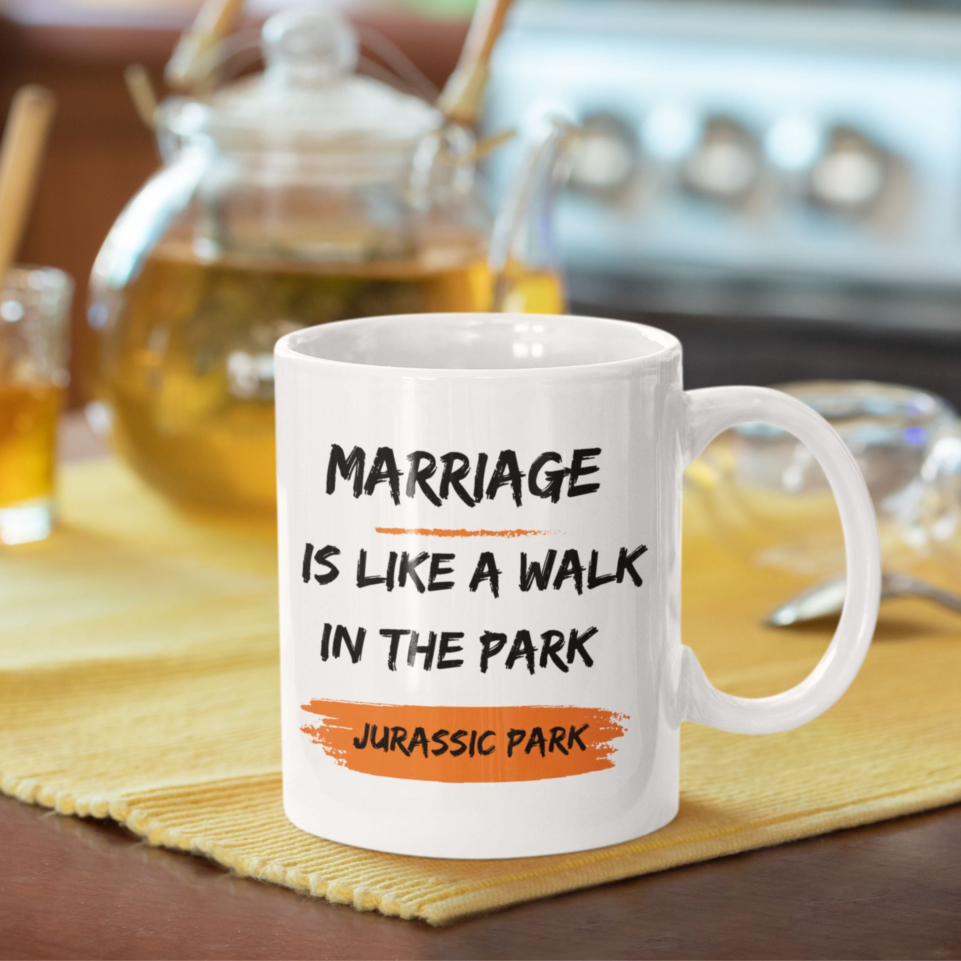 Funny 11oz Ceramic Coffee Mug on a kitchen counter with drinks, displaying 'Marriage is like a walk in the park, Jurassic Park' - perfect for joke gifts for men.