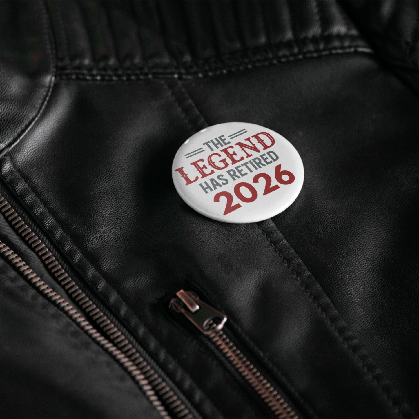 Button with 'The Legend Has Retired 2026' text on a black leather jacket.