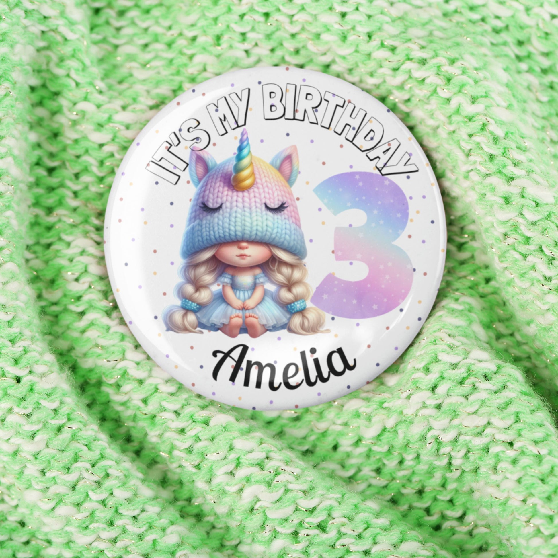 Button badge with unicorn design and text 'It's my birthday Amelia 3' on a green textured background