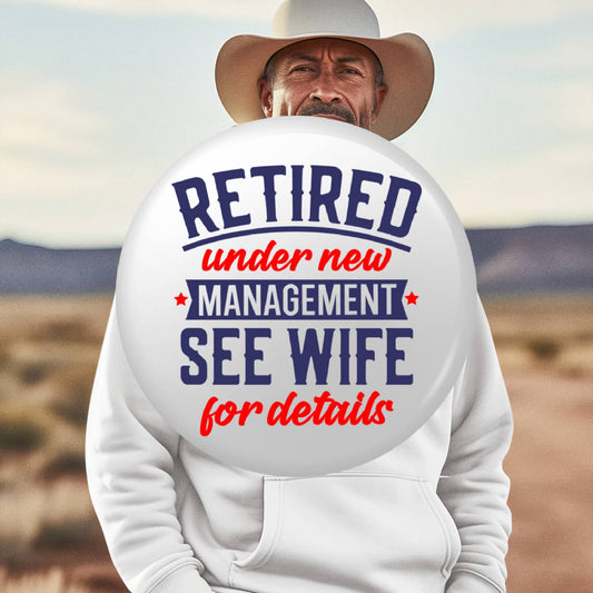 Retirement Badges: Heartfelt Thank You Gifts for Men - A man holding a badge that says 'Retired under new management, see wife for details' - Ideal farewell gift ideas for colleagues.