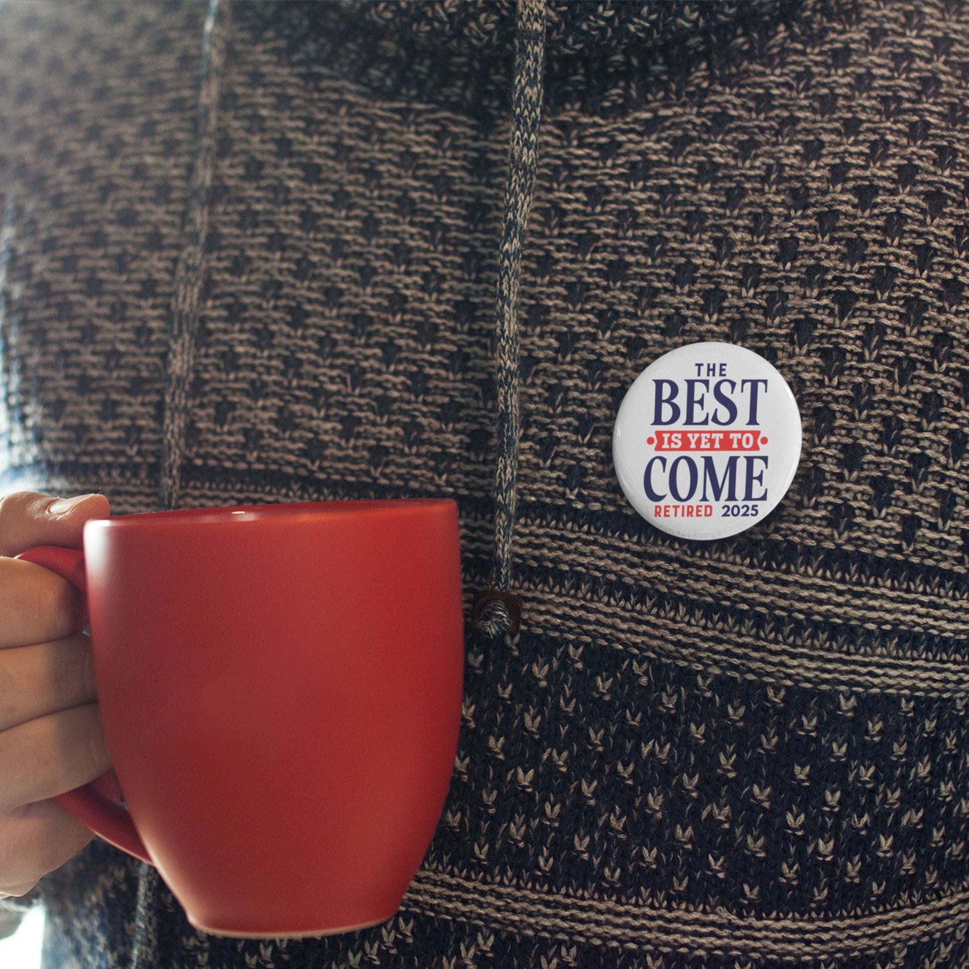 Happy Retirement Party Pin worn on a casual sweater while holding a red mug. A cheerful retirement party pin for relaxed gatherings.